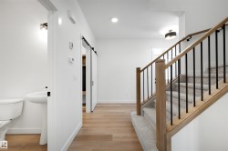 Modern staircase featuring wood-finish handrails and black metal balusters - 