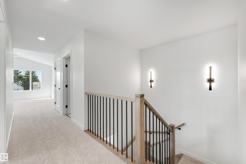 Carpeted hallway featuring a vaulted ceiling, recessed lighting, and a window providing natural illumination - 30 Elsinore Place, Edmonton, AB 