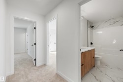 Modern bathroom featuring a wood-finish vanity with a white countertop and matte black hardware - 