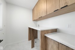Laundry area featuring light wood-finish cabinetry, white countertops, and light tile flooring - 