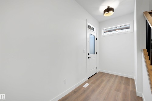 Entryway featuring light wood-finish flooring, white walls, and a white door with a frosted glass panel - 30 Elsinore Place, Edmonton, AB 