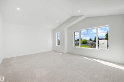 Spacious room featuring vaulted ceilings, recessed lighting, neutral carpeting, and a large window with multiple panes - 