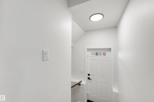 Entryway featuring a white paneled door with glass transom, black hardware, and a circular flush-mount ceiling light - 30 Elsinore Place, Edmonton, AB 