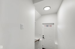 Entryway featuring a white paneled door with glass transom, black hardware, and a circular flush-mount ceiling light - 
