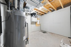 Utility room featuring a water heater, exposed ceiling joists, white drywall, concrete flooring, and visible ductwork - 