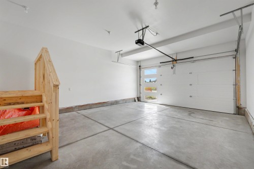 Spacious garage featuring a concrete floor, white walls, and an automatic garage door with frosted windows - 30 Elsinore Place, Edmonton, AB 
