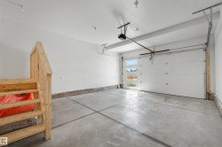 Spacious garage featuring a concrete floor, white walls, and an automatic garage door with frosted windows - 