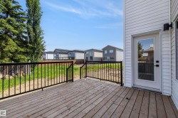 Expansive wooden deck featuring black metal railings and direct access to the interior via a glass-paneled door - 