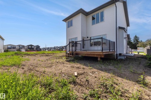 Two-story residence with white vinyl siding, a dark trim roofline, and a wooden deck featuring black railings - 30 Elsinore Place, Edmonton, AB 