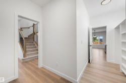 Foyer featuring light wood-finish flooring, white walls, and built-in shelving - 