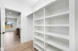 White built-in shelving offering extensive storage, complemented by light wood-finish flooring - 