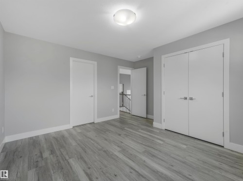 Spacious room featuring wood-finish flooring, light grey walls, and white trim - 2412 14 Avenue, Edmonton, AB 