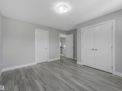 Spacious room featuring wood-finish flooring, light grey walls, and white trim - 