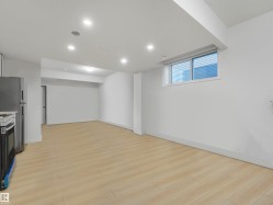 Open-concept living space featuring light wood-finish flooring, recessed lighting, and a contemporary window with horizontal blinds - 