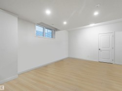 Spacious room featuring light wood-finish flooring, recessed lighting, and a white interior door - 