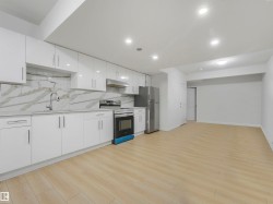 Open-concept living space featuring a contemporary kitchen with white high-gloss cabinetry, stainless steel appliances, and a marble-patterned backsplash - 
