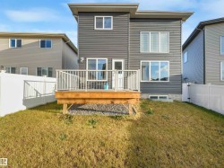 Rear exterior featuring dark gray horizontal siding and a ground-level wood deck with white railings - 