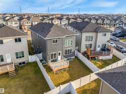 Rear exterior featuring a composite deck with railing, gray horizontal siding, multiple windows, and a fully fenced yard - 