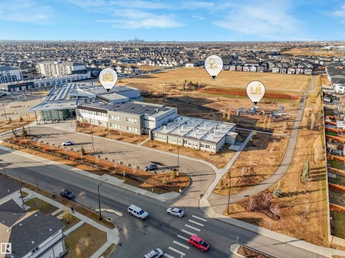 Expansive community grounds featuring a contemporary educational facility, paved pathways, and an outdoor play area - 2412 14 Avenue, Edmonton, AB 