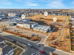 Expansive community grounds featuring a contemporary educational facility, paved pathways, and an outdoor play area - 