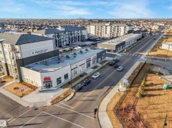 Modern commercial building featuring multiple storefronts and an upper-level residential apartment complex with individual balconies - 
