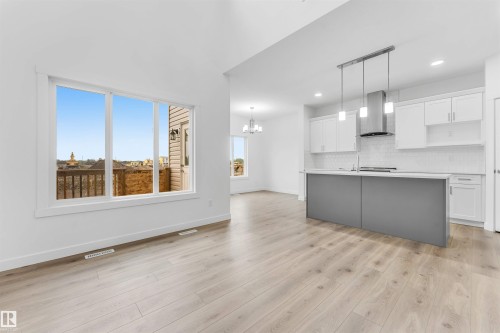 Bright interior featuring light wood-finish flooring, white walls, and a large multi-pane window - 1972 210 Street, Edmonton, AB 