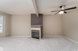Living room featuring a fireplace with a dark accent wall, light-toned carpeting, and a ceiling fan with integrated lighting - 