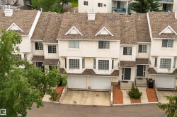 Townhome exterior featuring multiple bay windows, individual garages, and a neutral stucco finish - 