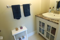 Vanity featuring a built-in white sink, multi-tone countertop, and white cabinetry with glass-paneled doors - 