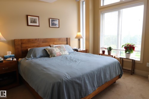 Expansive window wall with transom features, wood-finish flooring, recessed lighting, and warm neutral wall tones - 7492 May Common, Edmonton, AB 