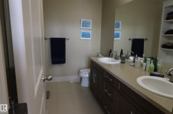 Bathroom featuring a double vanity with integrated sinks, a generous countertop, dark wood-finish cabinetry, and a spacious wall mirror - 