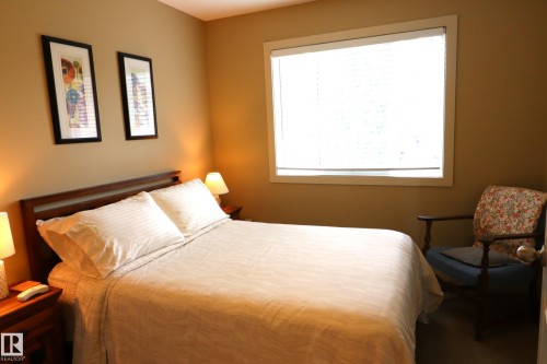 Bedroom featuring a large window with white blinds, neutral tone walls, and a recessed ceiling light fixture - 7492 May Common, Edmonton, AB 