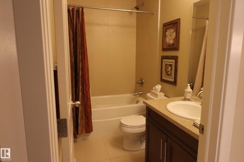 Full bathroom featuring a single vanity with a white basin, dark wood-finish cabinetry, and a light-toned countertop - 7492 May Common, Edmonton, AB 