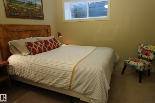 Wood-paneled headboard with an angular design, carpeted flooring, and a single window offering natural light - 7492 May Common, Edmonton, AB 