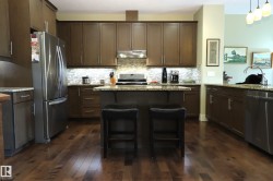 Kitchen featuring wood-finish flooring, dark wood cabinetry, and stainless steel appliances - 