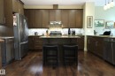 Kitchen featuring wood-finish flooring, dark wood cabinetry, and stainless steel appliances - 7492 May Common, Edmonton, AB 