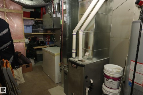 Utility room featuring a furnace with visible ductwork, a water heater, and built-in shelving - 7492 May Common, Edmonton, AB 