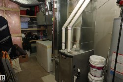 Utility room featuring a furnace with visible ductwork, a water heater, and built-in shelving - 
