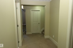 Carpeted hallway featuring light-toned walls, white trim, and a prominent arched door frame - 