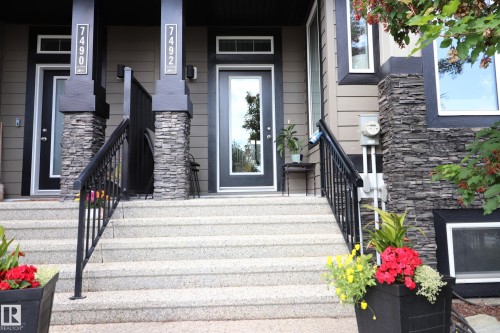 Exterior entry featuring a glass-panel door, stone-clad columns, and exposed aggregate steps - 7492 May Common, Edmonton, AB 