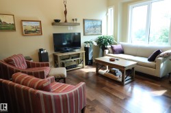 Bright living area featuring wood-finish flooring, a floating wall shelf, and expansive windows - 