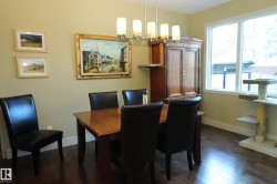 Dining area featuring wood-finish flooring, a contemporary chandelier, and a large window - 