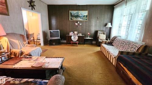 Interior room featuring wood paneling, wall-to-wall carpeting, and a window with sheer curtains - 9522 110 Avenue Nw, Edmonton, AB - Indoor Photo Showing Living Room