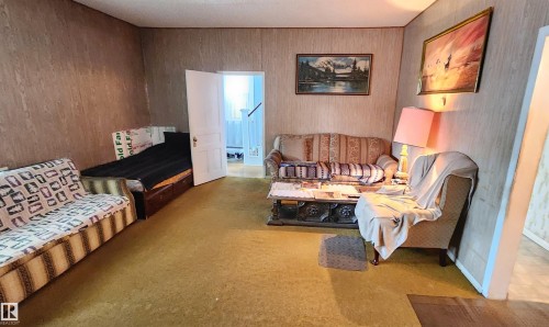 Spacious room featuring textured wall paneling and a doorway opening to an additional interior space - 9522 110 Avenue Nw, Edmonton, AB - Indoor