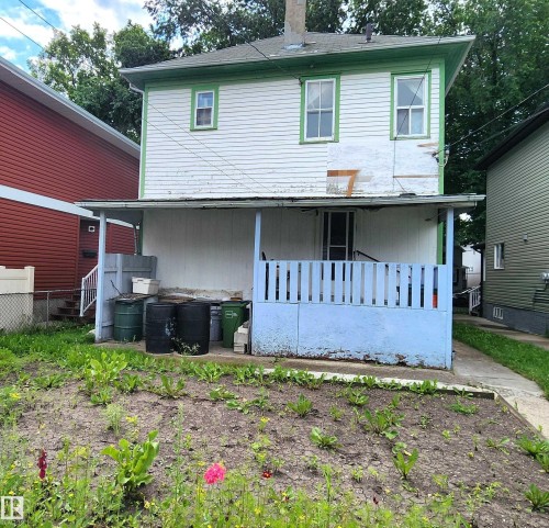 Two-story structure featuring white siding with green trim and a covered porch - 9522 110 Avenue Nw, Edmonton, AB - Outdoor With Exterior