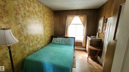 Room featuring wood-finish paneling, a single window, and floral-patterned wall covering - 9522 110 Avenue Nw, Edmonton, AB - Indoor