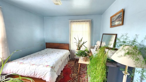 Interior room featuring a single window with vertical blinds, light blue walls, and a recessed baseboard heater - 9522 110 Avenue Nw, Edmonton, AB - Indoor Photo Showing Bedroom
