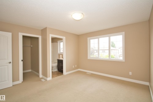 Spacious bedroom with neutral-toned walls, plush carpeting, and a large multi-pane window - 11513 17 Avenue, Edmonton, AB 