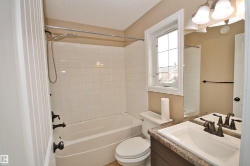Bathroom featuring a white subway tile shower surround, a built-in bathtub, and an integrated window - 11513 17 Avenue, Edmonton, AB 