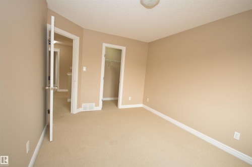 Carpeted room featuring neutral wall paint, white baseboards, and a semi-flush mount ceiling light - 11513 17 Avenue, Edmonton, AB 